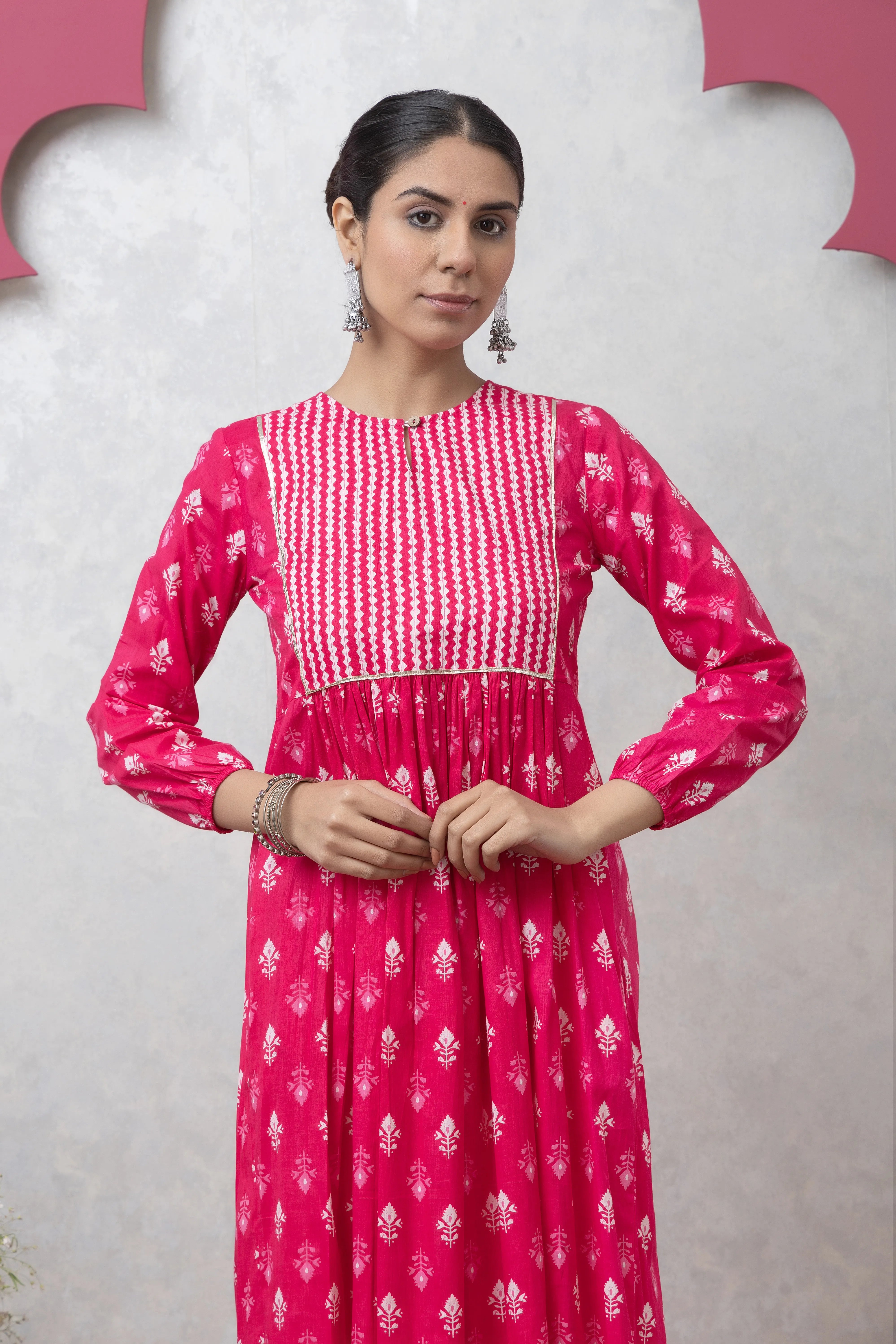 Woman wearing a pink and white patterned dress against a light gray background