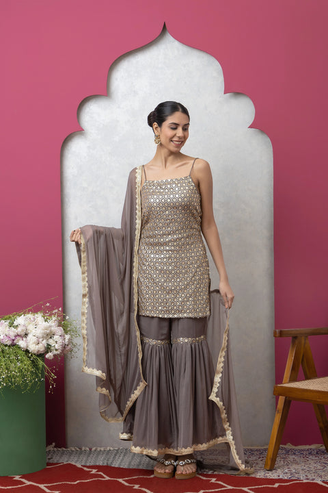 Woman in traditional outfit with a pink wall and decorative mirror in the background