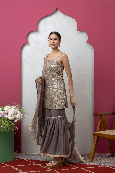 Woman in traditional outfit with a pink wall and decorative mirror in the background