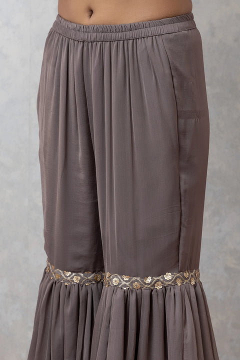 Brown pleated skirt with decorative waistband on a gray background