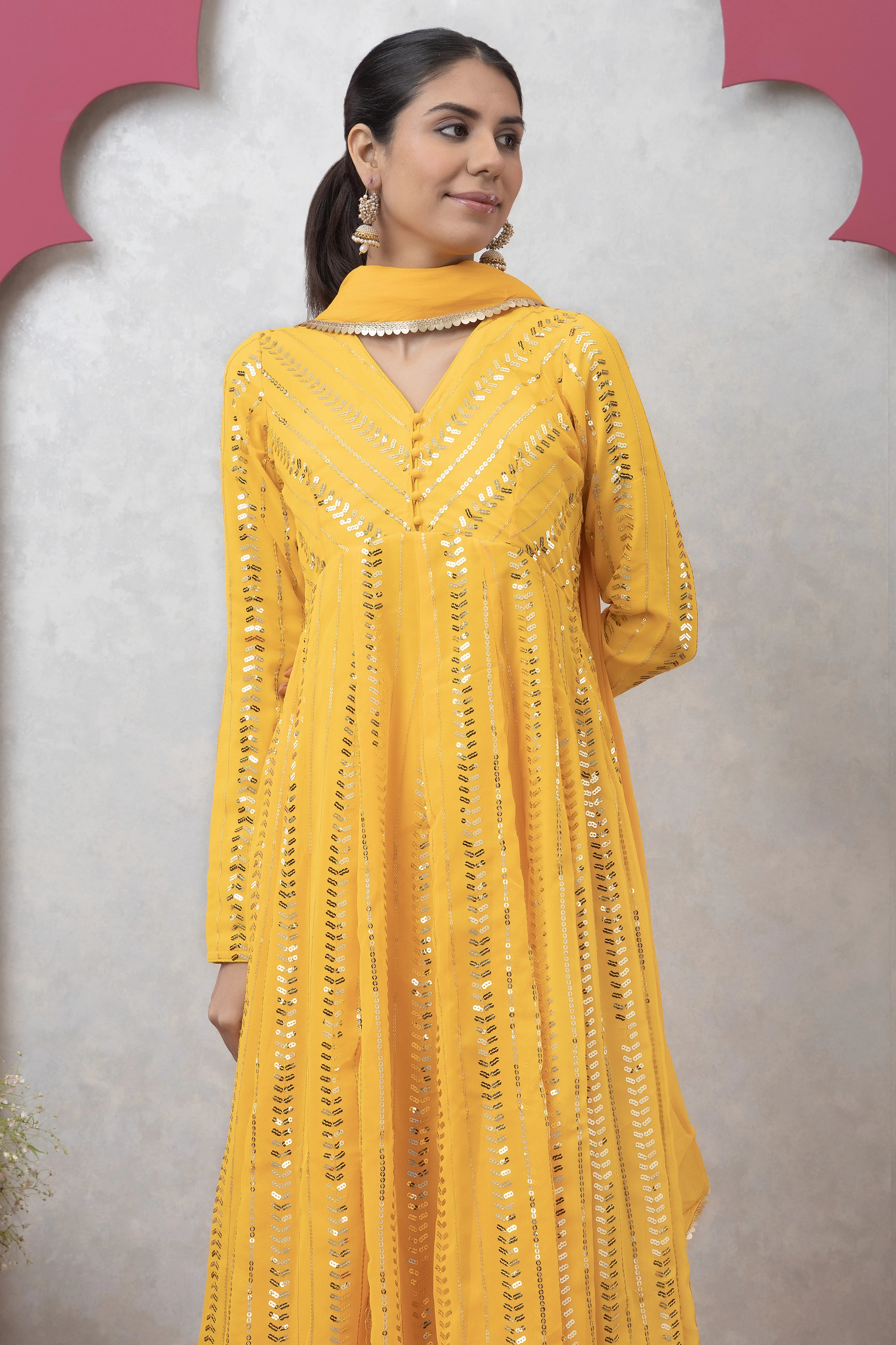 Woman wearing a yellow embroidered dress against a gray background