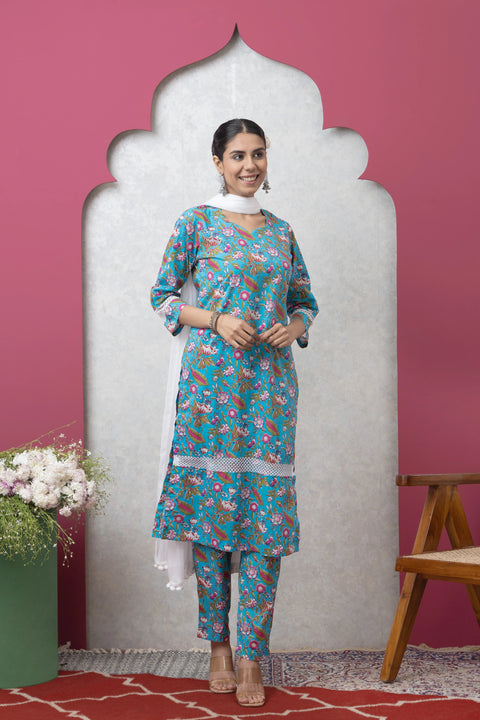 Woman wearing a floral outfit standing against a pink wall with decorative elements.