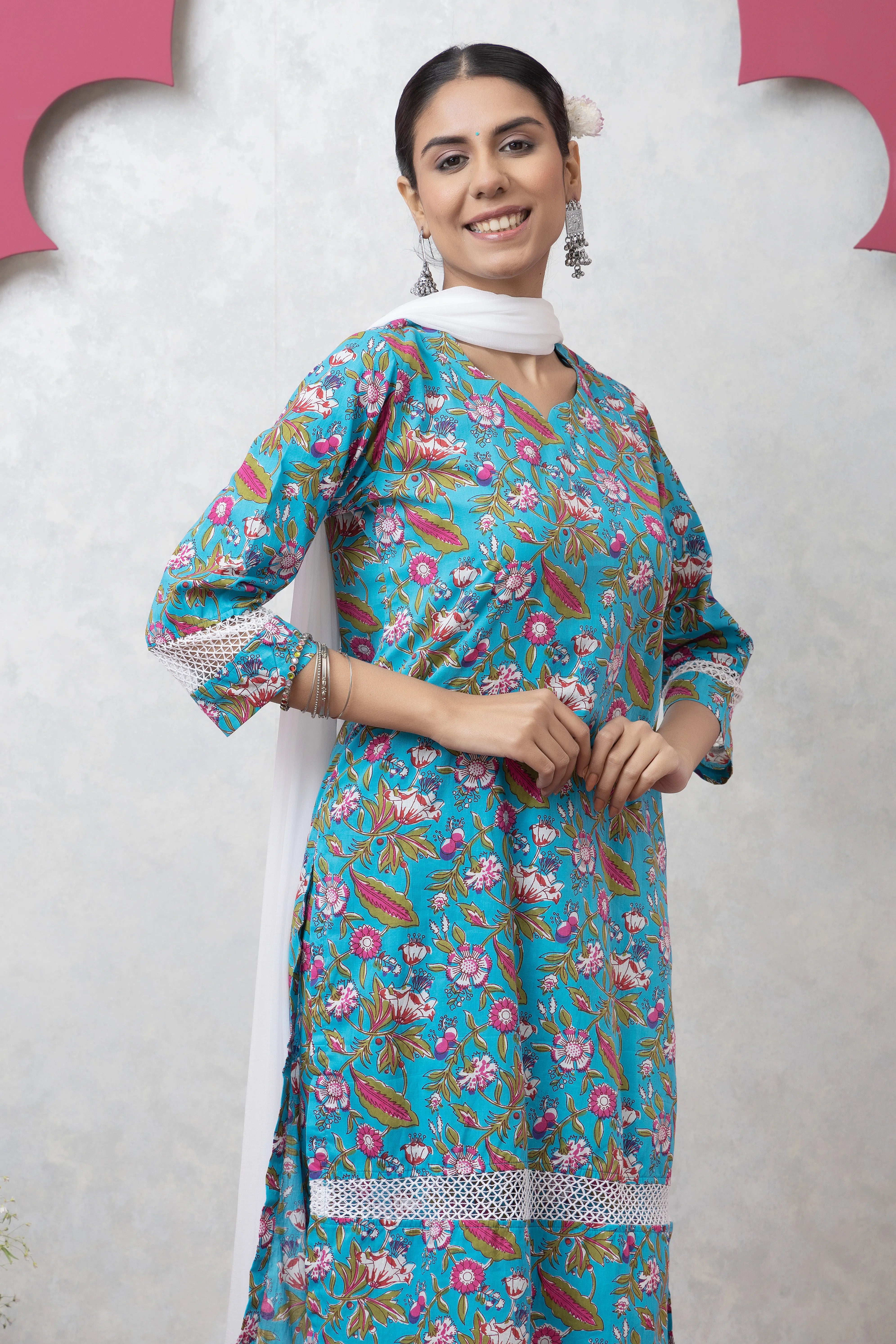 Woman wearing a floral dress with a white scarf against a light gray background