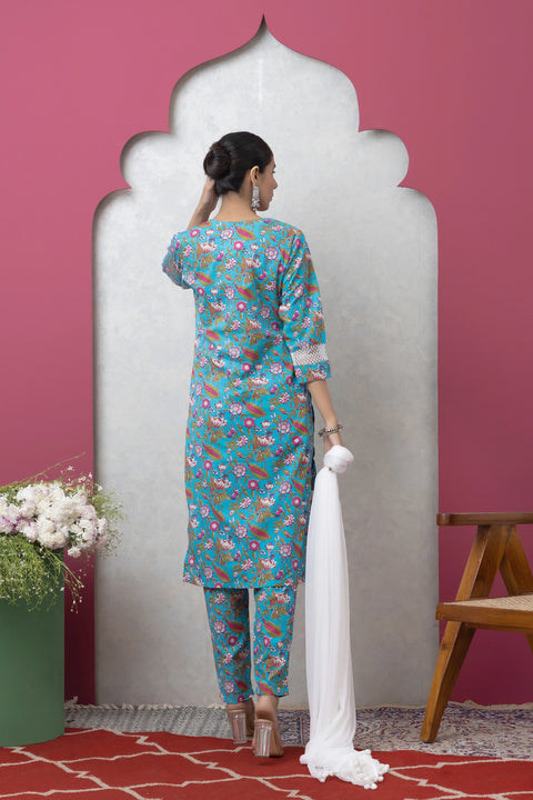 Woman in a blue floral outfit standing against a pink wall with a white arch.