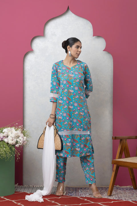 Woman in a floral dress standing against a pink wall with a white arch.