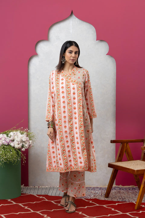 Woman in a patterned outfit standing in front of a decorative archway with a pink wall and red rug.
