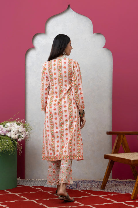 Woman wearing a patterned kurta with pants against a pink wall.