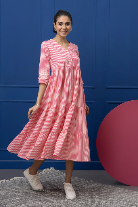 Woman wearing a pink striped dress against a blue wall.