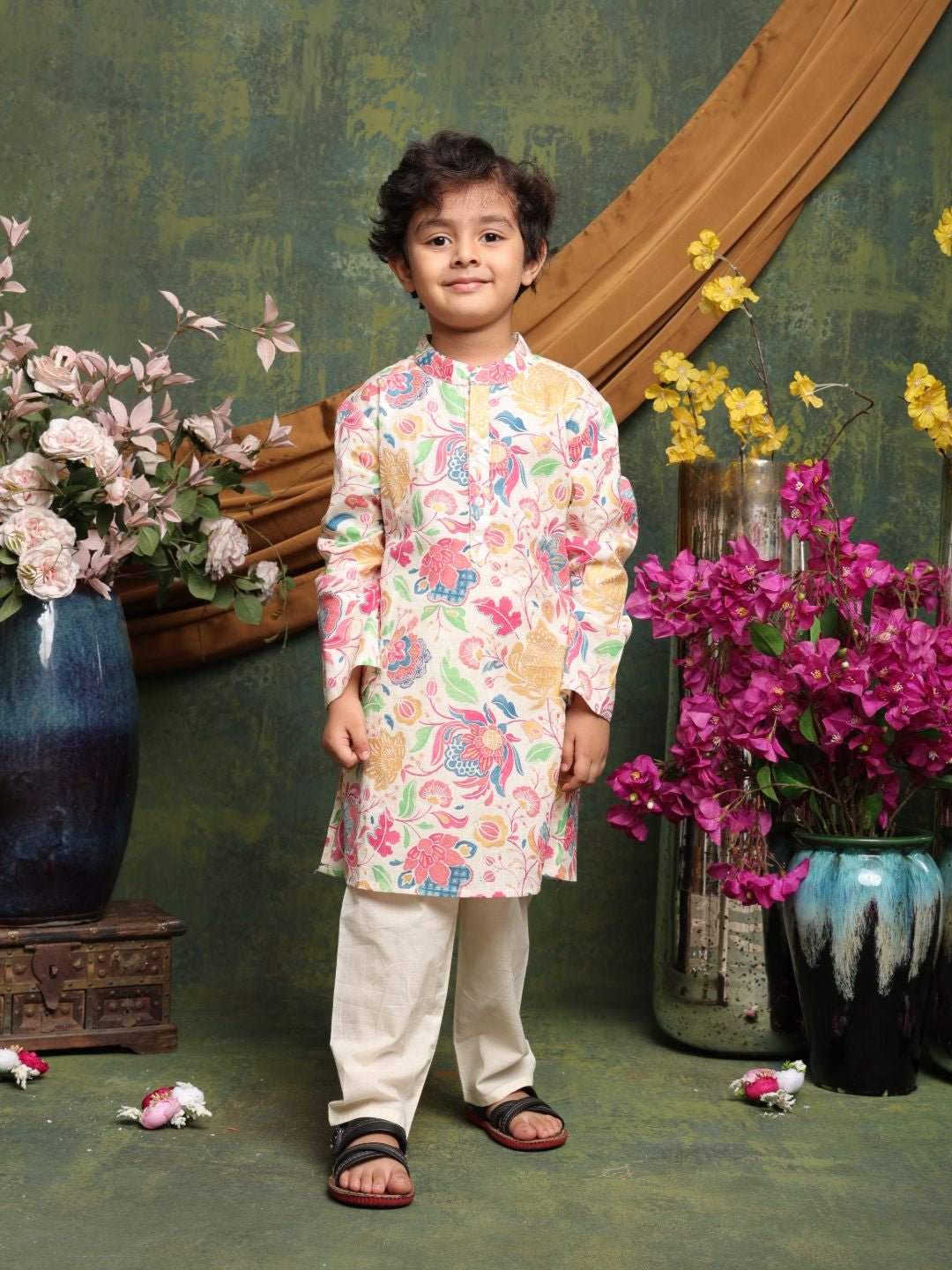 Child wearing a colorful traditional outfit standing in front of floral decorations