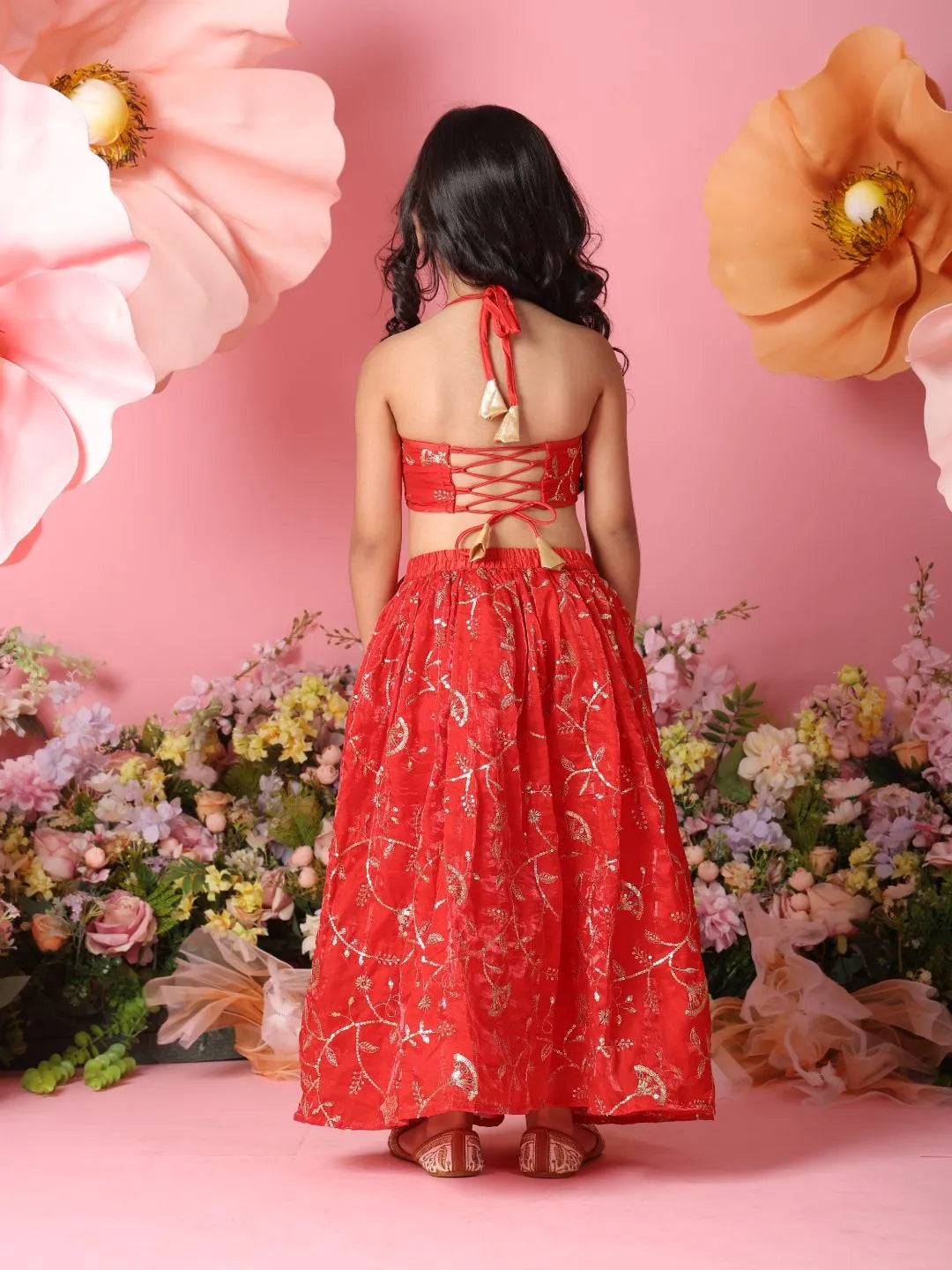 Woman in a red dress standing against a pink floral backdrop