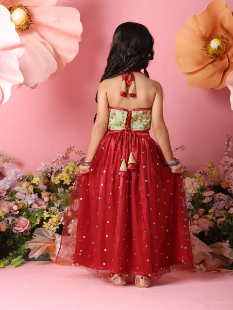 Woman in a red dress with floral top against a pink background with flowers