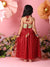 Woman in a red dress with floral top against a pink background with flowers