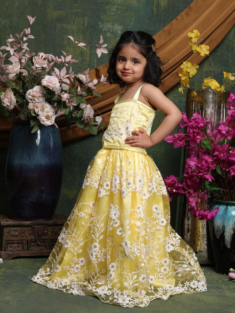 Young girl in a yellow floral dress standing among flowers and decorative vases.