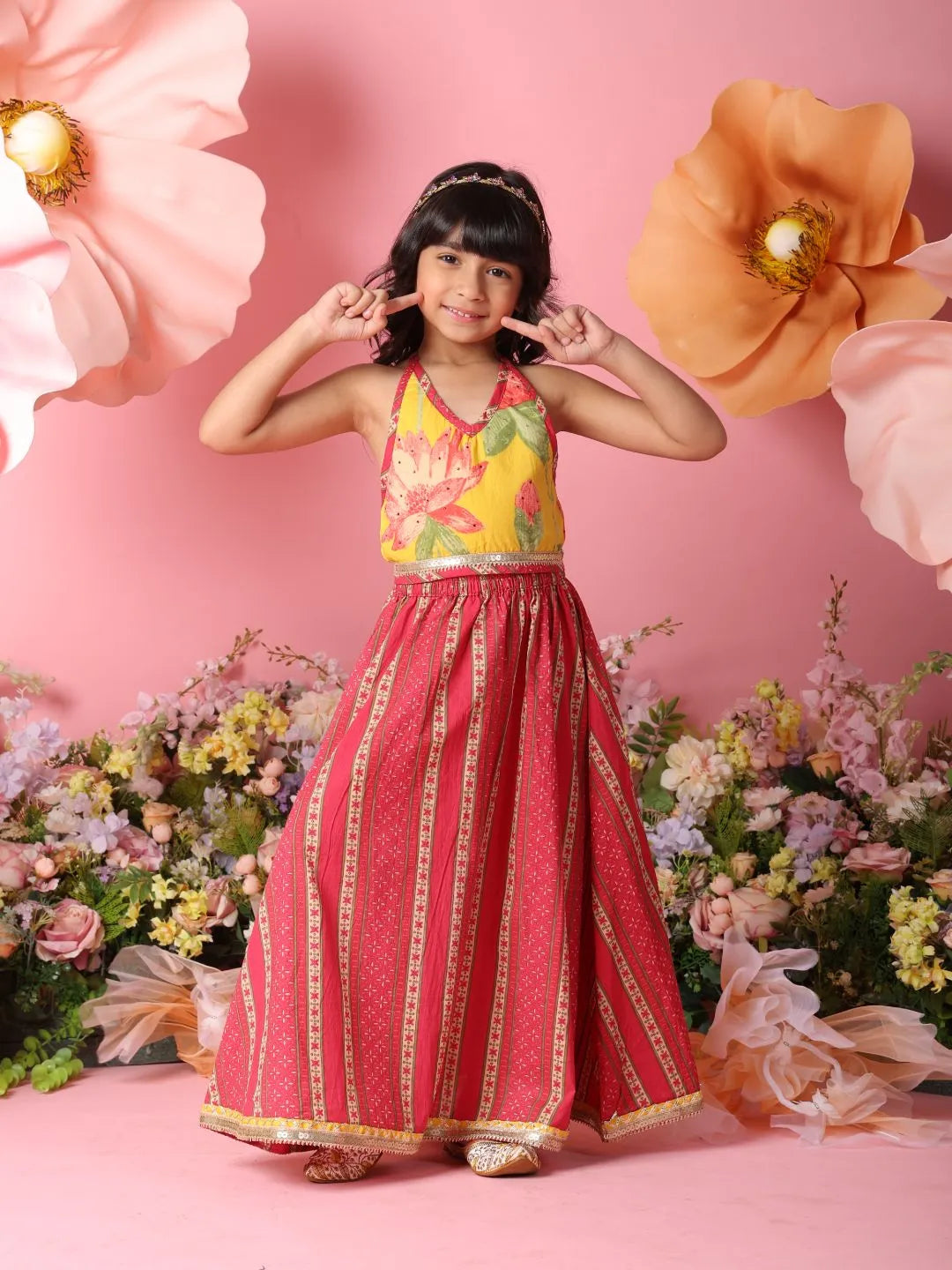 Young girl in a colorful traditional outfit against a pink floral background