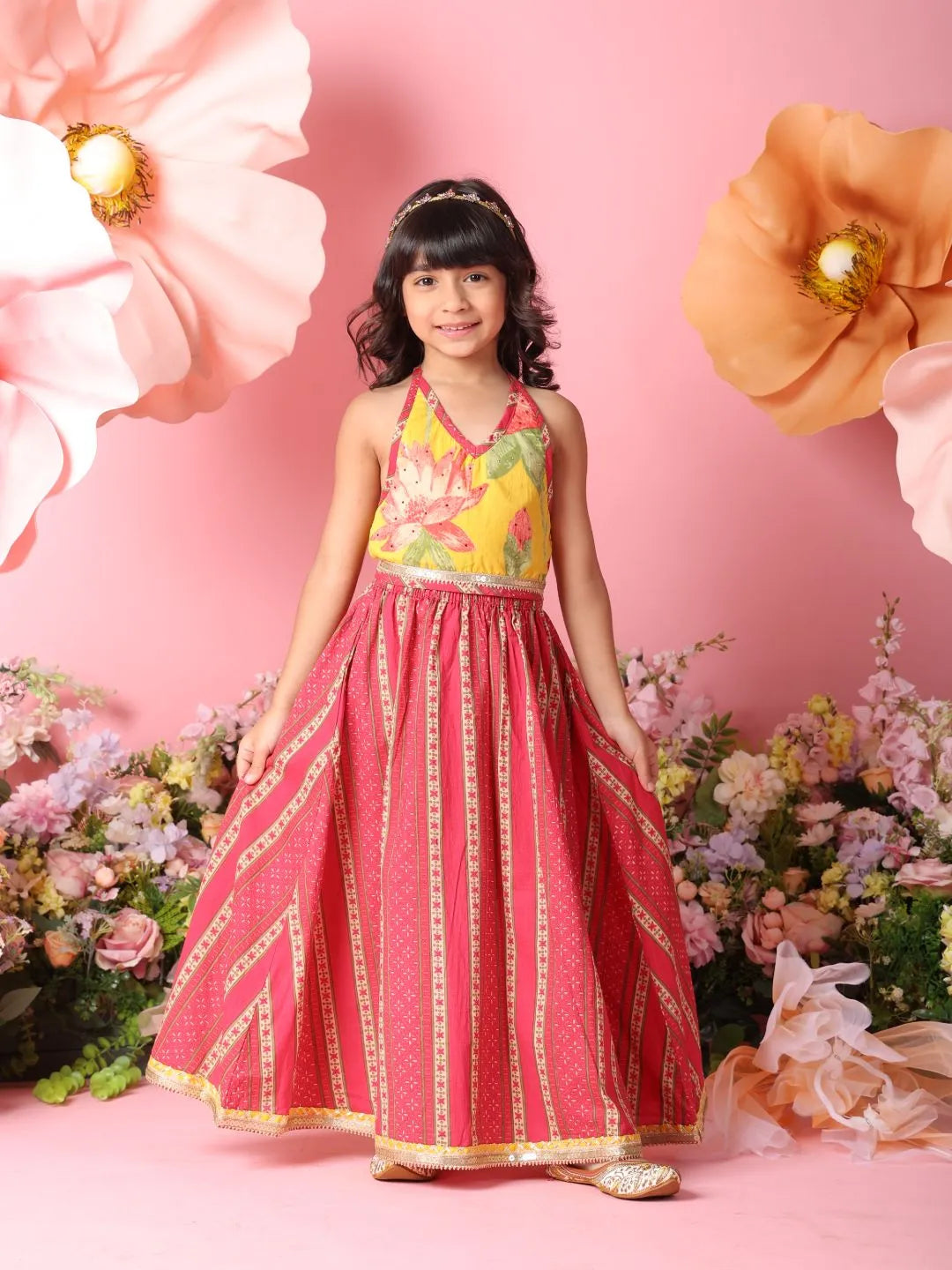 Young girl in a floral dress standing against a pink background with flowers