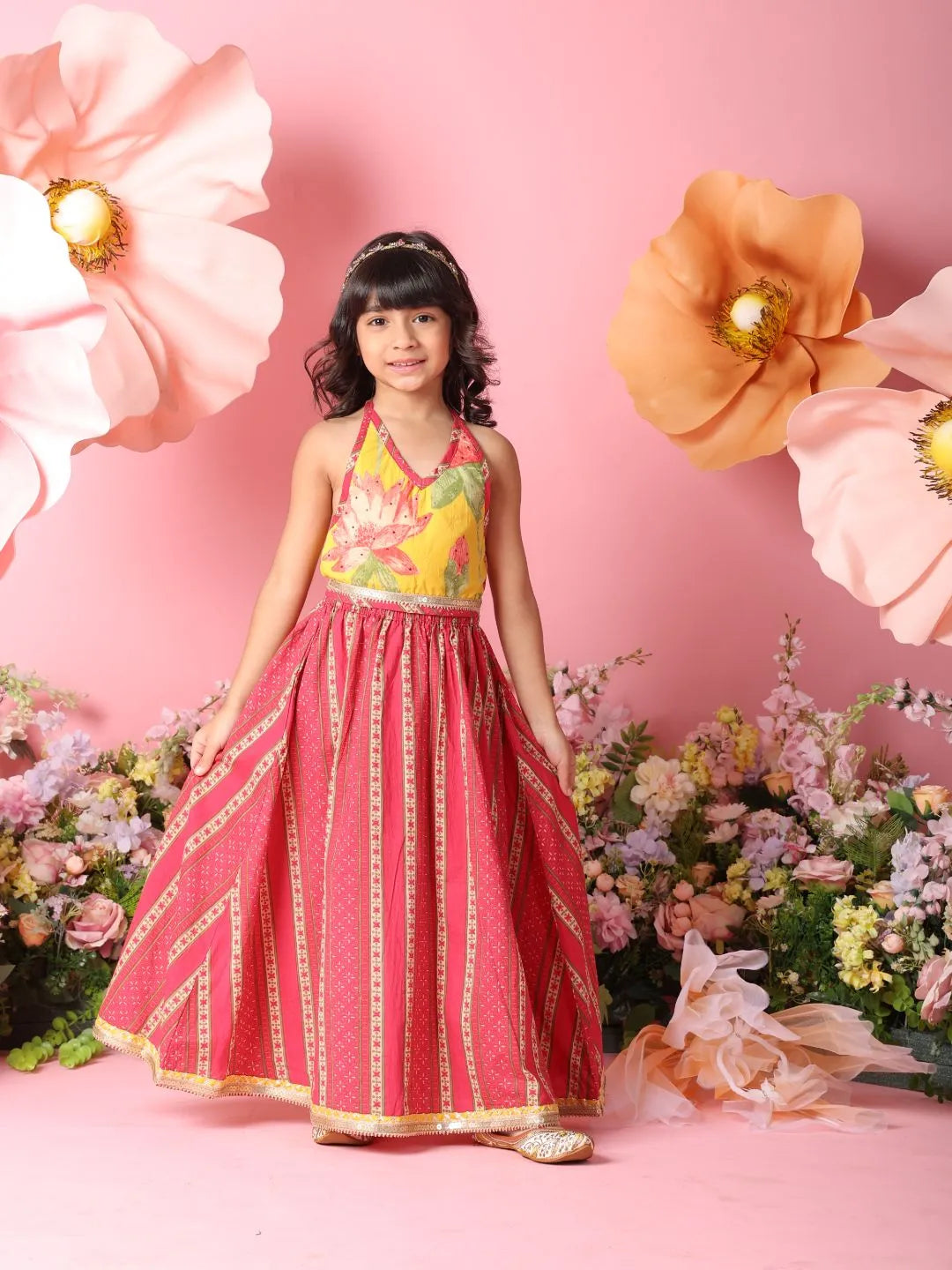 Young girl in a floral dress standing against a pink background with flowers