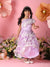 Young girl in a floral dress standing among flowers and oversized flowers on a pink background