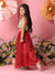 Young girl in a green top and red skirt standing against a pink background with flowers.