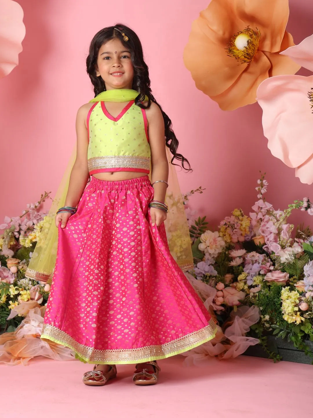 Young girl in a pink and green traditional outfit with flowers in the background