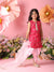 Young girl in a pink traditional outfit standing against a floral backdrop with a pink background