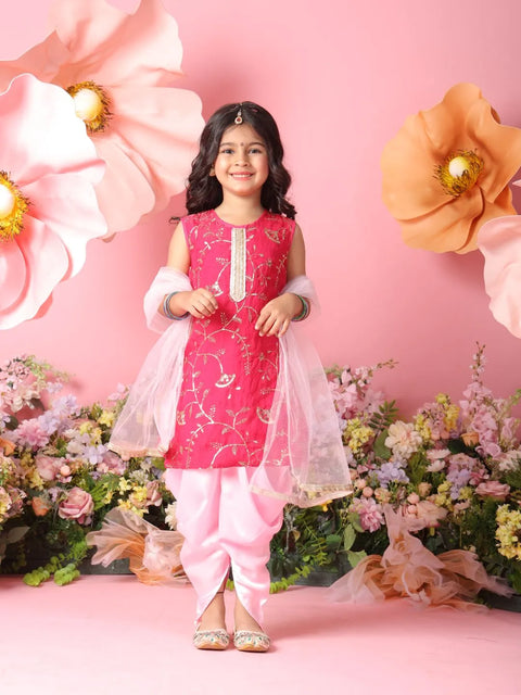Young girl in a pink traditional outfit standing against a floral and pink flower backdrop