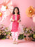 Young girl in a pink traditional outfit standing against a floral and pink flower backdrop