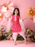 Young girl in a pink traditional outfit standing against a pink floral backdrop