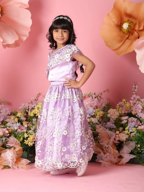 Young girl in a purple floral dress standing in front of a pink background with flowers.