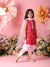 Young girl in a red and pink traditional outfit standing against a pink background with flowers.