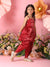 Young girl in a red traditional outfit standing in front of floral decorations on a pink background