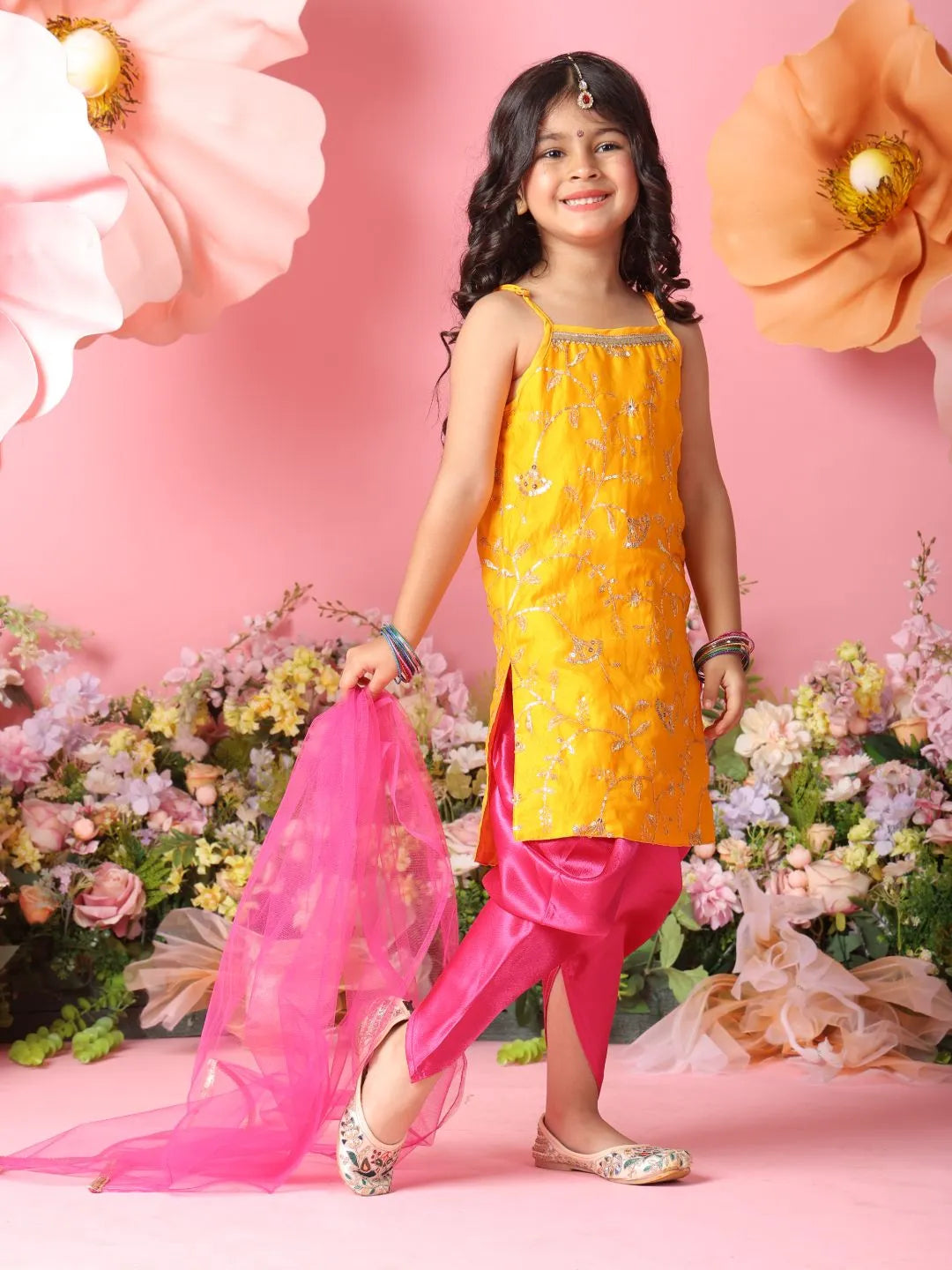 Young girl in a yellow and pink traditional outfit with flowers and pink background