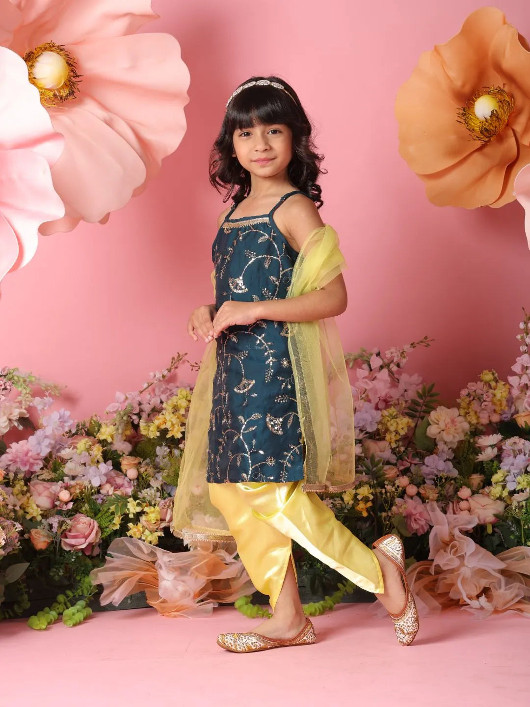 Young girl in traditional outfit with floral decorations and pink background